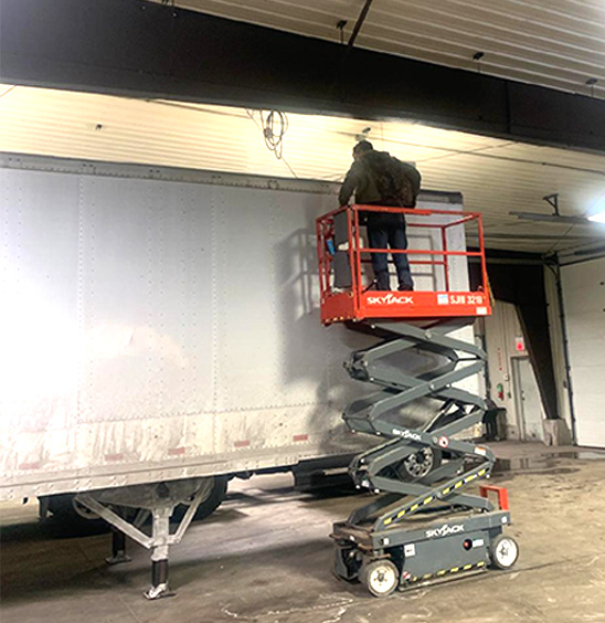 Man on lift repairing trailer